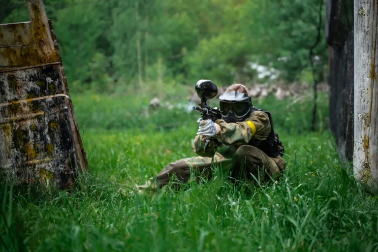 The player shoots a gun on the battlefield in a paintball
