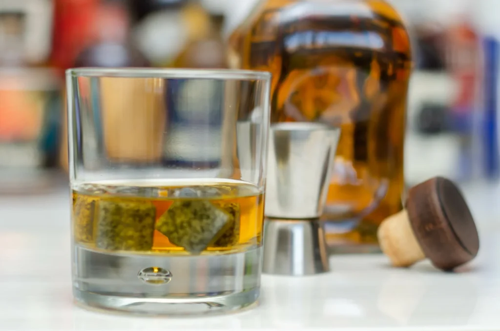 Bicchiere old fashioned con scotch whisky e cubetti di ghiaccio al bar
